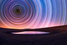 Beautiful Night Landscape, Old Volcano, Crater Lake. The Colorful Star Trails On The Sky. Night Timelapse Photography.