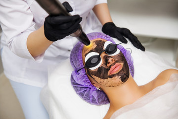 Process of carbon face laser peeling procedure in beauty salon. Laser pulses clean skin of the face. Hardware cosmetology treatment. Facial skin rejuvenation, warming the skin