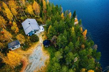 Aerial View Of Cottage In Autumn Colors Forest By Blue Lake In Rural Finland