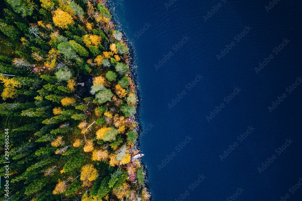 Aerial view of cottage in autumn colors forest by blue lake in rural Finland - obrazy, fototapety, plakaty 