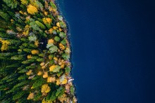 Aerial View Of Cottage In Autumn Colors Forest By Blue Lake In Rural Finland