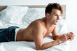 © LIGHTFIELD STUDIOS - sexy young man in blue jeans lying on bed at home