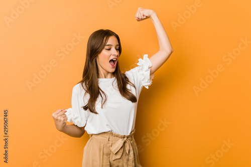 Cuadros en Lienzo Young caucasian woman raising fist after a victory, winner concept