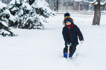 Wall Mural - boy with a shovel playing outside in the snow