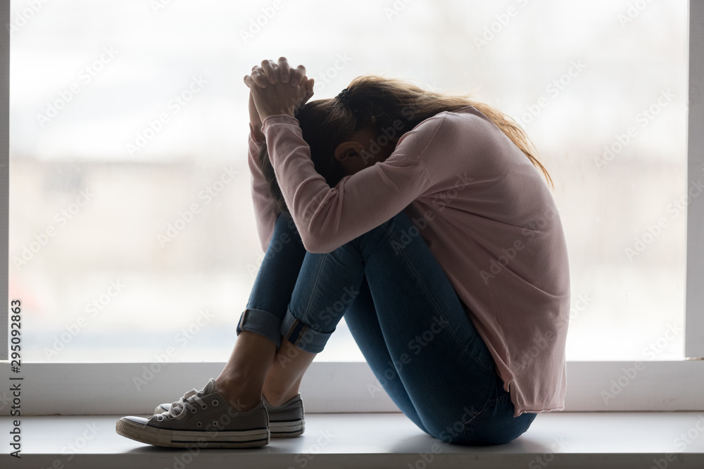 Depressed sad teen girl sit on sill crying at home - obrazy, fototapety, plakaty 
