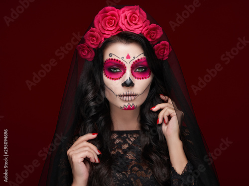 Fotografía Portrait of a woman with sugar skull makeup over red background