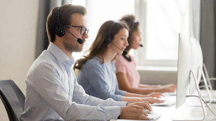 Wall Mural - side view call center employees working using computers and headsets