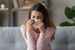 © fizkes - Allergic ill woman holding tissue blowing running nose