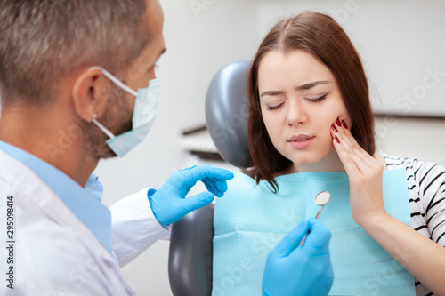 Cuadros en Lienzo Young woman having toothache, sitting in a dental chair at the clinic