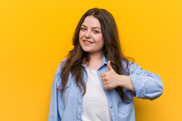 Wall Mural - Young curvy plus size woman smiling and raising thumb up