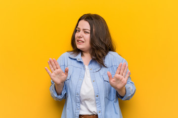 Wall Mural - Young curvy plus size woman rejecting someone showing a gesture of disgust.