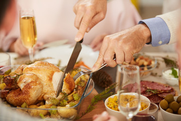 Wall Mural - Close-up of man cutting turkey in the dish with cutting knife before eating