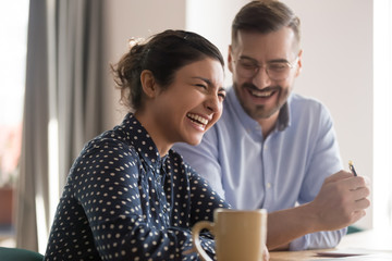 Poster - Happy young indian business woman laughing with male colleague in office