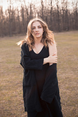 Wall Mural - A young woman in black clothes walks across the field