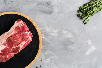 Raw meat beef on a cutting board with rosemary and spices. Top view, flat lay, mockup, copy space. Food concept