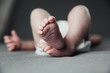 © Сергей Уланов - Newborn baby belly and legs in diaper, lying on white bed, top view, copy space