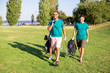 © Mangostar - Happy friendly volunteers carrying litter from city park. Young men and woman walking on grass, holding rakes, plastic bags, smiling. Rubbish removal concept