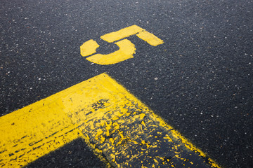 Number five yellow painted on street, road sign on asphalt