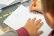 © kwarkot - A boy writes English words by hand on traditional white paper in a notebook. The boy writes his first test on English. Child writing, spelling and education. Boy learns english. English writing skills