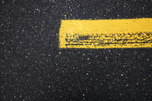 Abstract Background With Yellow Lines, Street With Dark And Wet Aspalt With A Yellow Painted Line