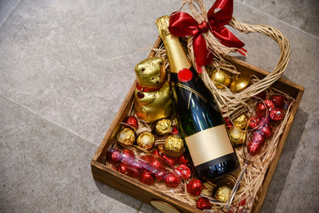 Bottle of champagne with candies and ornaments gift placed in wooden box