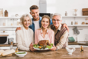 smiling family members holding plate with tasty turkey in Thanksgiving day