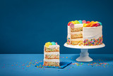 Fototapeta Tęcza - Colorful Birthday Cake with Slice and Sprinkles