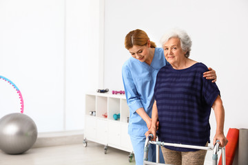 Canvas Print - Caretaker helping elderly woman with walking frame indoors