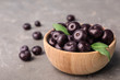 Bowl of fresh acai berries on grey stone table, closeup view. Space for text