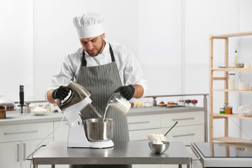 Wall Mural - Male pastry chef preparing dough in mixer at kitchen table