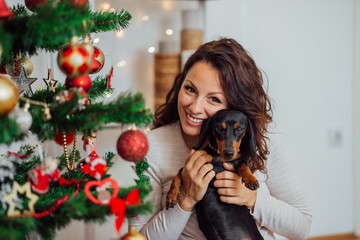 Christmas portrait of cute smiling woman and her dog.