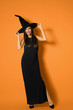 © New Africa - Beautiful woman wearing witch costume for Halloween party on yellow background