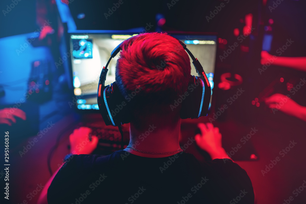 Professional gamer playing online games tournaments pc computer with headphones, Blurred red and blue background - obrazy, fototapety, plakaty 