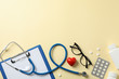 Stethoscope and medicines on yellow background, top view. Doctor workplace