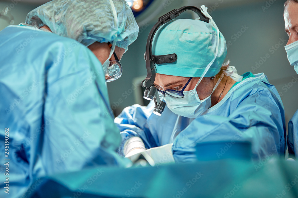 Group of surgeons looking at patient on operation table during their ...