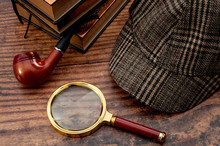 Literary Fiction, Police Inspector, Investigate Crime And Mystery Story Conceptual Idea With Sherlock Holmes Detective Hat, Smoking Pipe, Retro Magnifying Glass And Book Isolated On Wood Table Top