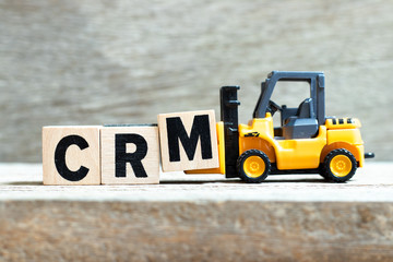 Canvas Print - Toy forklift hold letter block M to complete word CRM (Abbreviation of Customer Relationship Management) on wood background