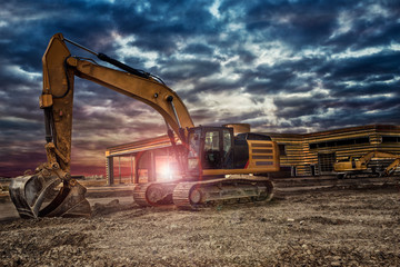 Excavating machinery at the construction site, sunset in background.