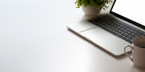 Canvas Print - cropped shot of minimal workspace with laptop computer and tree pot on white table table
