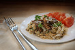 risotto replacement for the low carb diet made from cauliflower with porcini mushrooms, parsley and tomatoes on a plate, dark rustic table