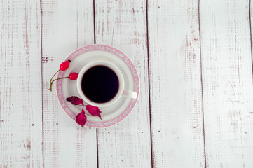 Cup of coffee on a wooden background with autumn leaves and barberry