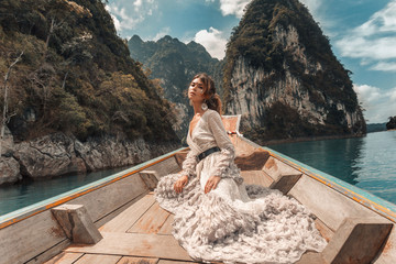 fashionable young model in elegant dress on boat at the lake