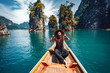 Leinwandbild Motiv happy young woman tourist in asian hat on the boat at lake