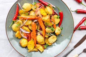 warm salad of baked potatoes and carrots with red onions, spices and tomatoes