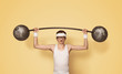 © rangizzz - Funny retro sport nerd lifting weights over yellow background with copy space