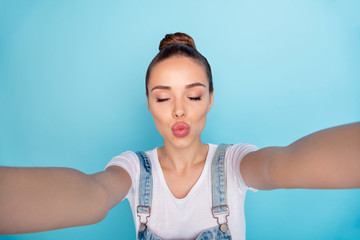 Sticker - Self portrait of cute charming flirty tempting girl kissing you via camera while isolated with blue background