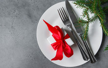 Fork Knife, Gift Box With Red Ribbon On White Plate, Fir Branches On Gray Background Christmas Decor,