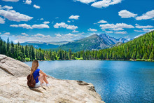 Girl Relaxing On The Rock By Lake In Beautiful Mountains. Young Woman Enjoying Nature On Hiking Trip. Bear Lake. Estes Park. Rocky Mountains National Park, Colorado, USA.