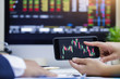 © manusapon - Businessman checking stock market data. He using a mobile phone. Analysis economy data on forex earn graph.