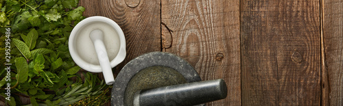 Fotografía panoramic shot of white and grey mortars with pestles on wooden surface with fre